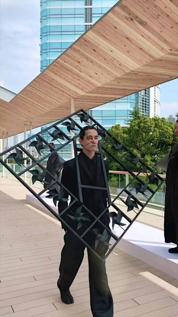 【東コレ取材】「ヨシオクボ（YOSHIOKUBO）」は“風”がテーマの８ルックを発表。風ぐるまが付いた木組のピースを肩にかけたルックは、歩くといっせいに風ぐるま