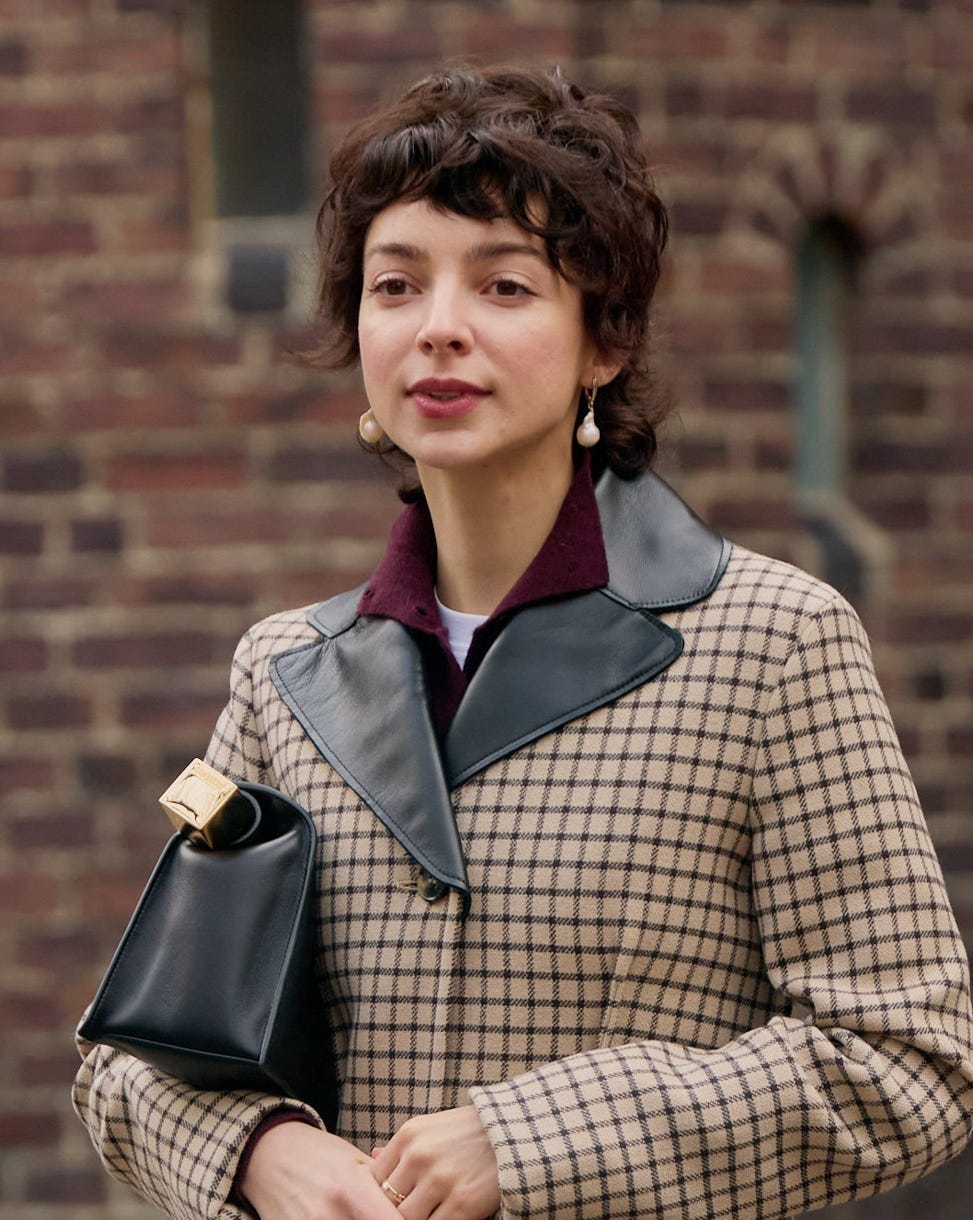 fashionable person in a checked coat holding a stylish handbag