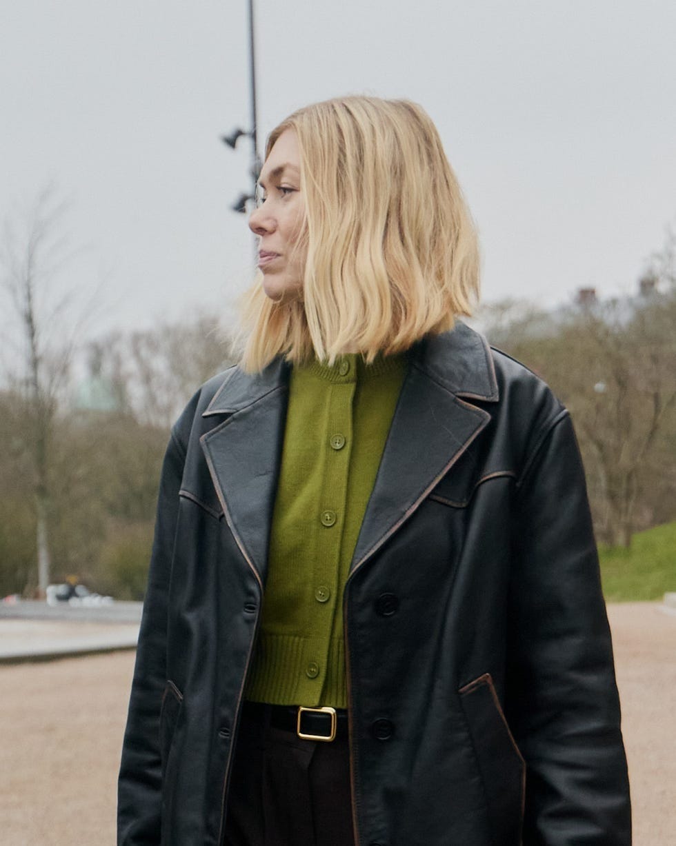 fashionable individual in a black leather coat and green cardigan