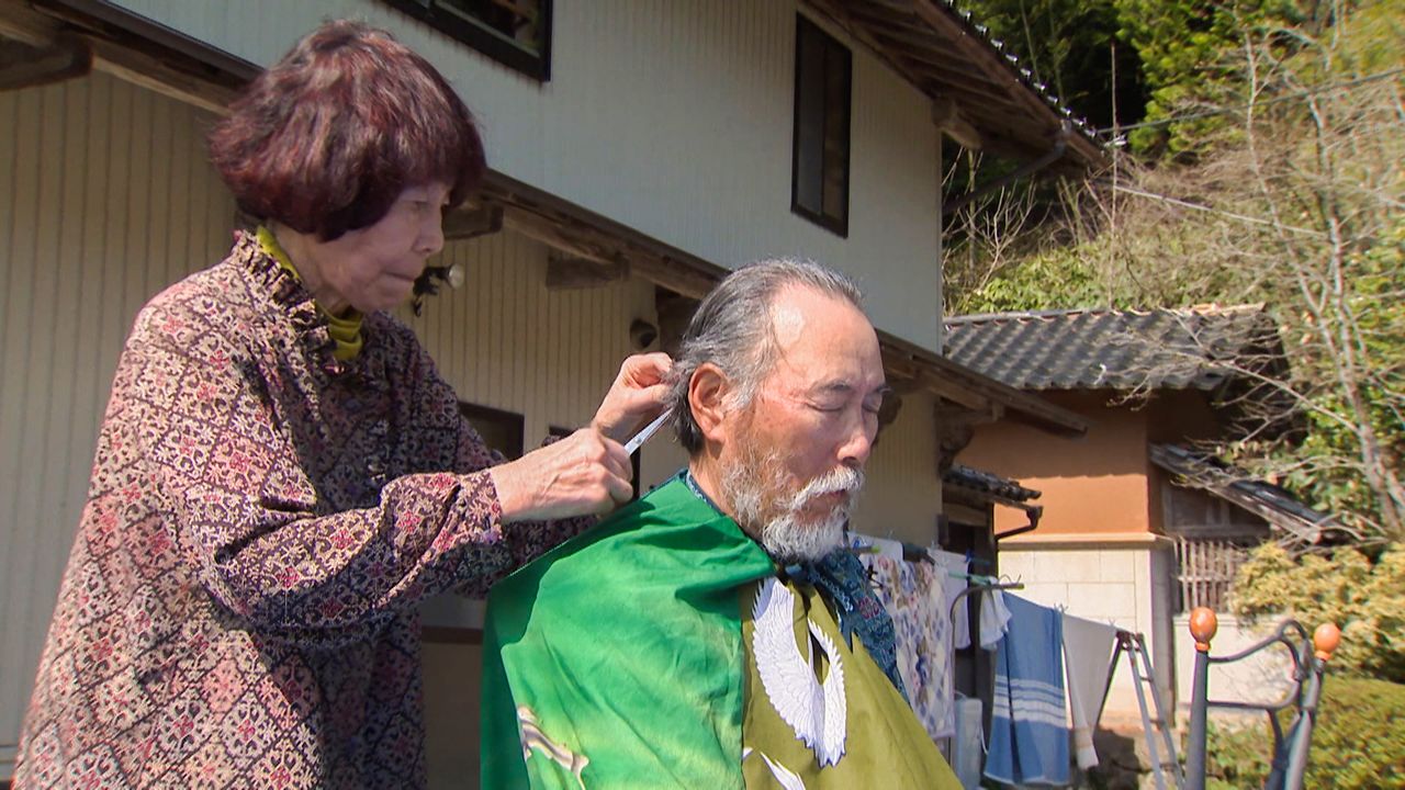 震災後、ボランティアに明け暮れた夫の散髪をする順子さん　©石川テレビ放送
