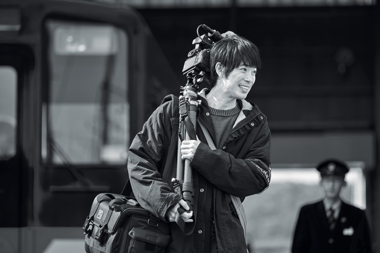 カメラを担ぎ、近隣の暮らしを取材して回る駒井は中尾監督の分身的存在　©2025 ぴあ、ホリプロ、日活、電通、博報堂、一般社団法人PFF