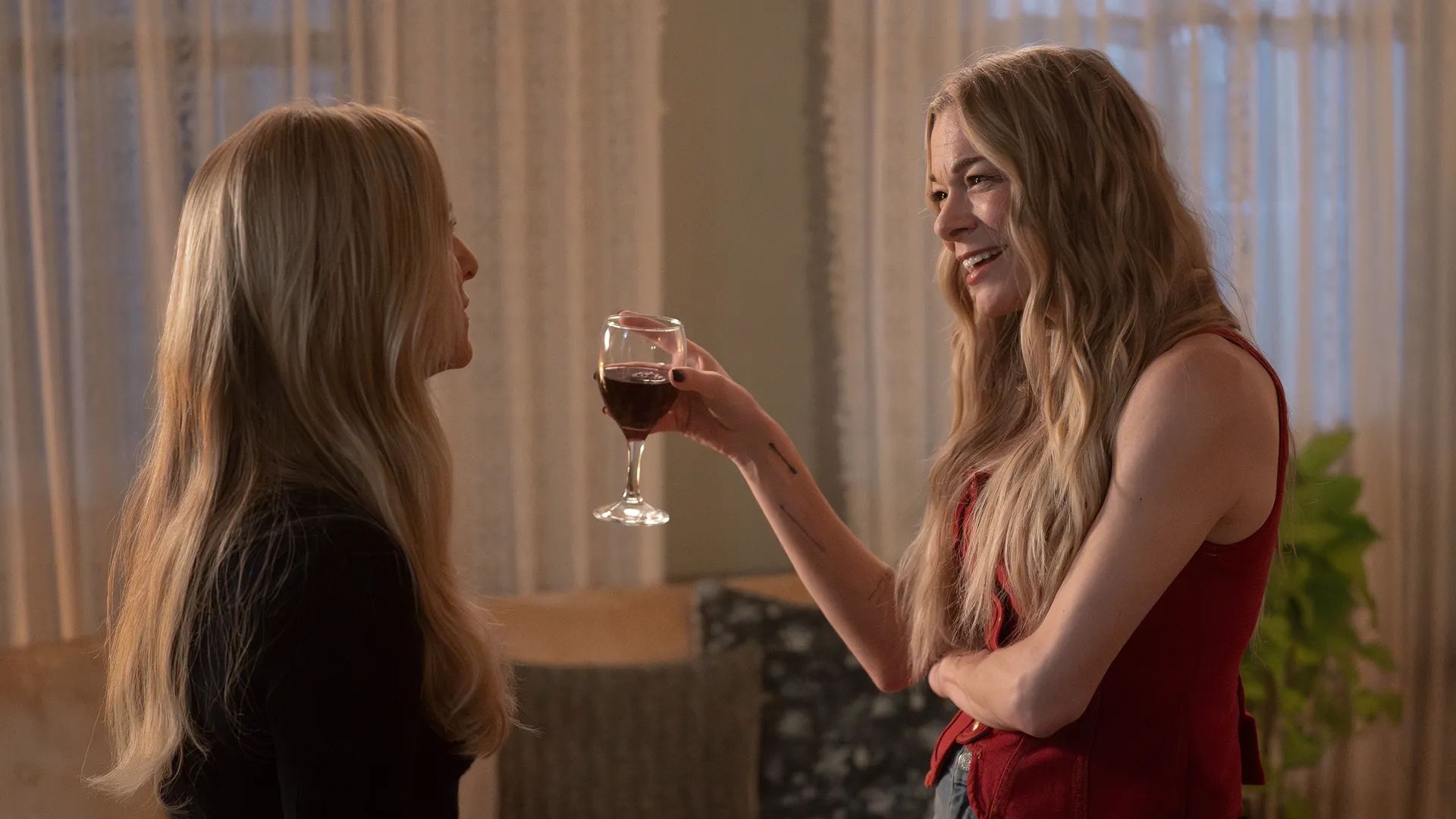 Blythe Hart (Jessica Capshaw) talks to a smiling Dixie Bennings (LeAnn Rimes), who is holding a glass of wine.