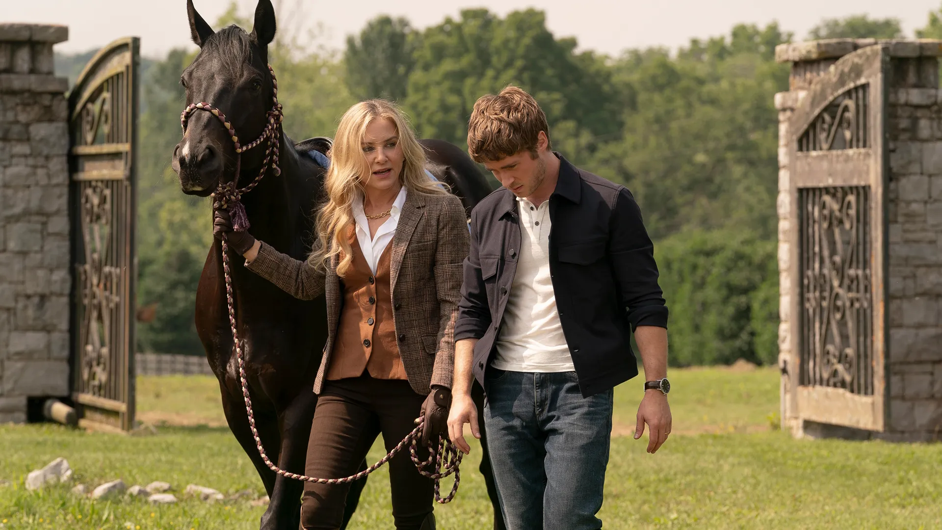 Blythe Hart (Jessica Capshaw), dressed in riding gear and leading a horse, talks to Ryan Hart (Michael Provost) in a field.